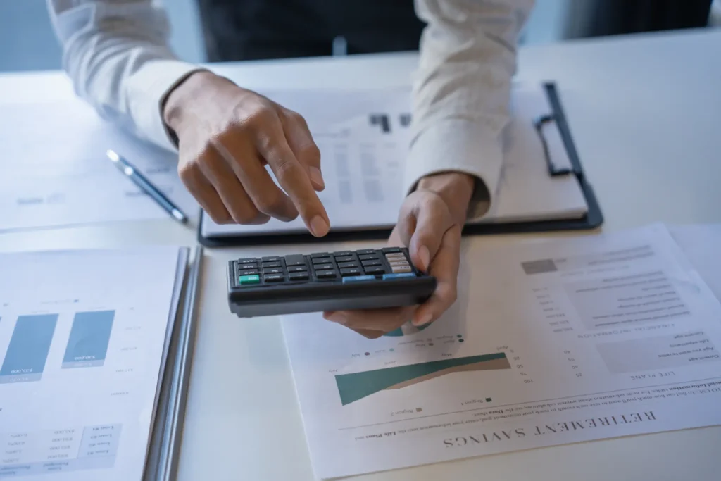 Manos de un experto analizando datos con calculadora para el informe de prevención de blanqueo de capitales.